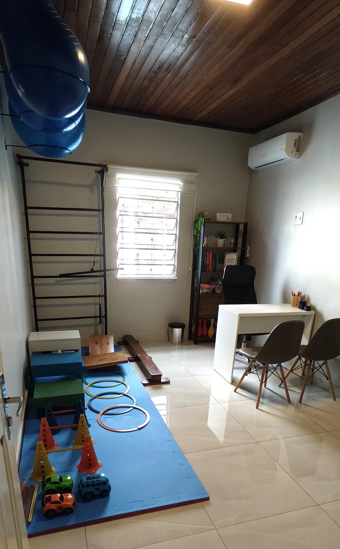 Sala de terapia da Progride com tatame azul, cones, argolas e materiais para atividades motoras