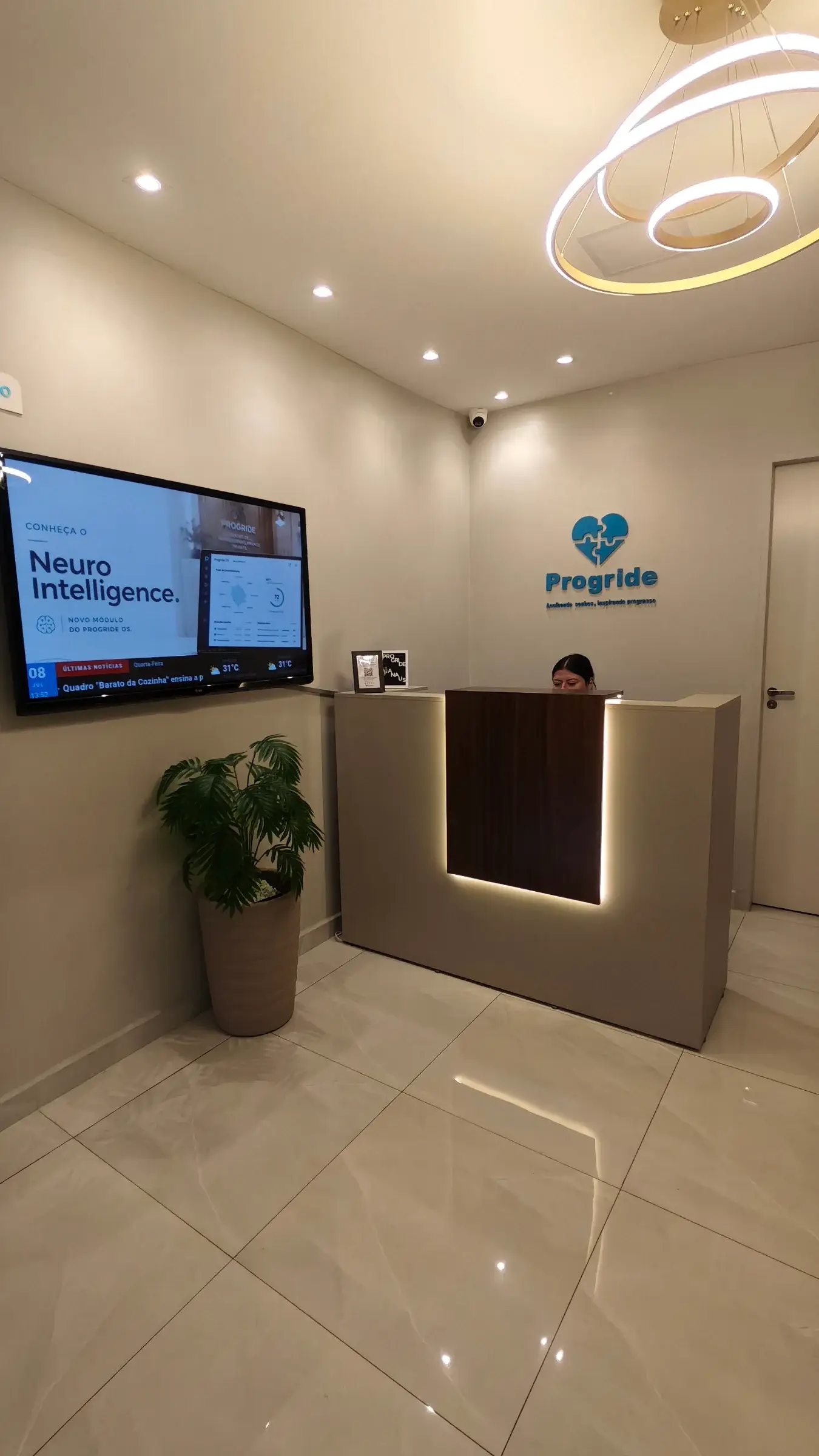 Recepção da Progride com o logotipo na parede e o balcão de atendimento iluminado