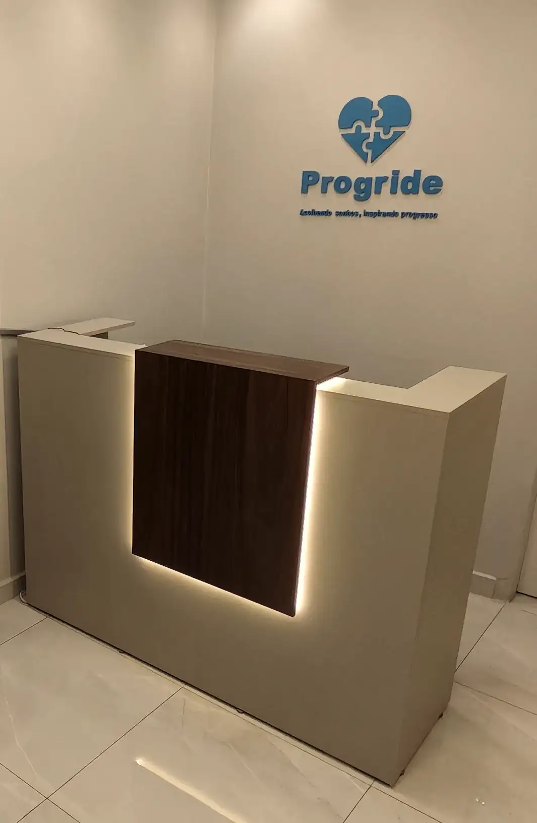 Recepção da Progride com balcão e marca da clínica na parede