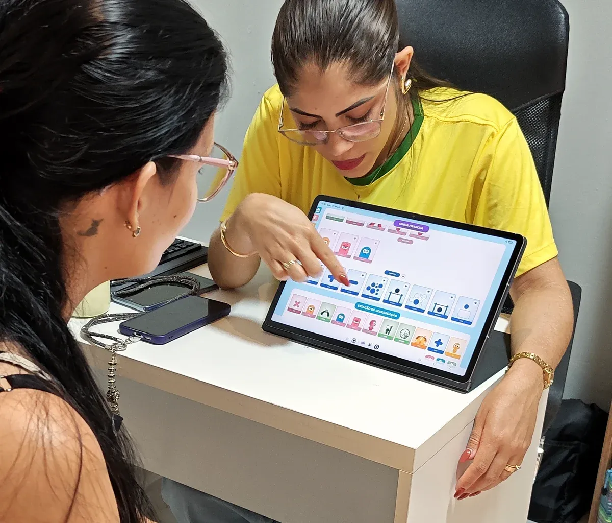 Profissional da Progride conversa com uma mãe durante uma orientação, com apoio de um tablet